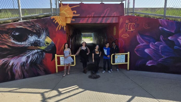 L to R: Lacey Jane Wilburn, Layla Folkmann, Leanne Kembel, Wesley Vizcrra and Lolu Awoderu in front of the entrance to the tunnel by Father Leonard Van Tighem School on June 13, 2025. (Photo: J. Goulet, My Lethbridge Now)